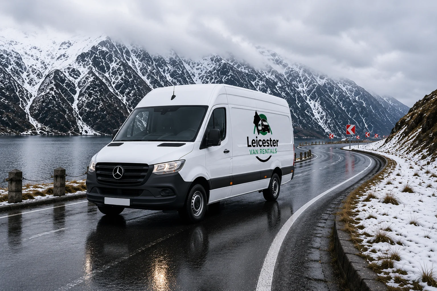 White Mercedes-Benz Sprinter medium panel van from Leicester Van Rentals driving on a wet mountain road beside a lake with snow-covered peaks in the background.